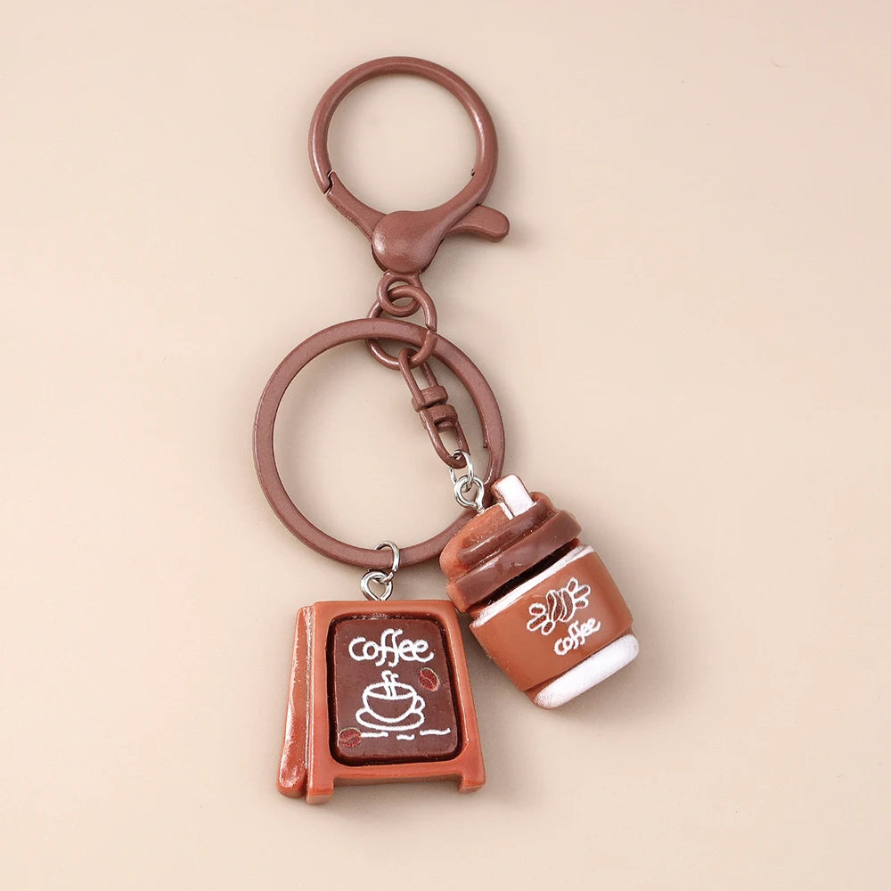 A brown leather coffee cup keychain with a hanging loop and charm.