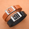 A brown leather belt with a silver metal pin buckle is shown on a beige background.