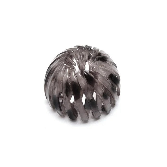 A close-up of elegant dark gray horsetail hair clips coiled into a decorative spiral.