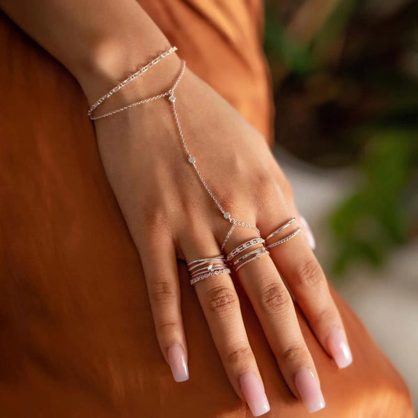 Gros plan d'une main portant un bracelet charm en argent sterling géométrique.