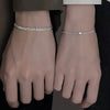 A pair of dainty stainless steel heart link bracelets worn on a person's wrists.