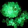 A pile of luminous glow-in-the-dark green acrylic beads on a dark background.