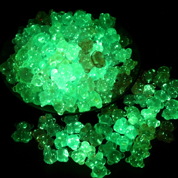 A pile of luminous glow-in-the-dark green acrylic beads on a dark background.