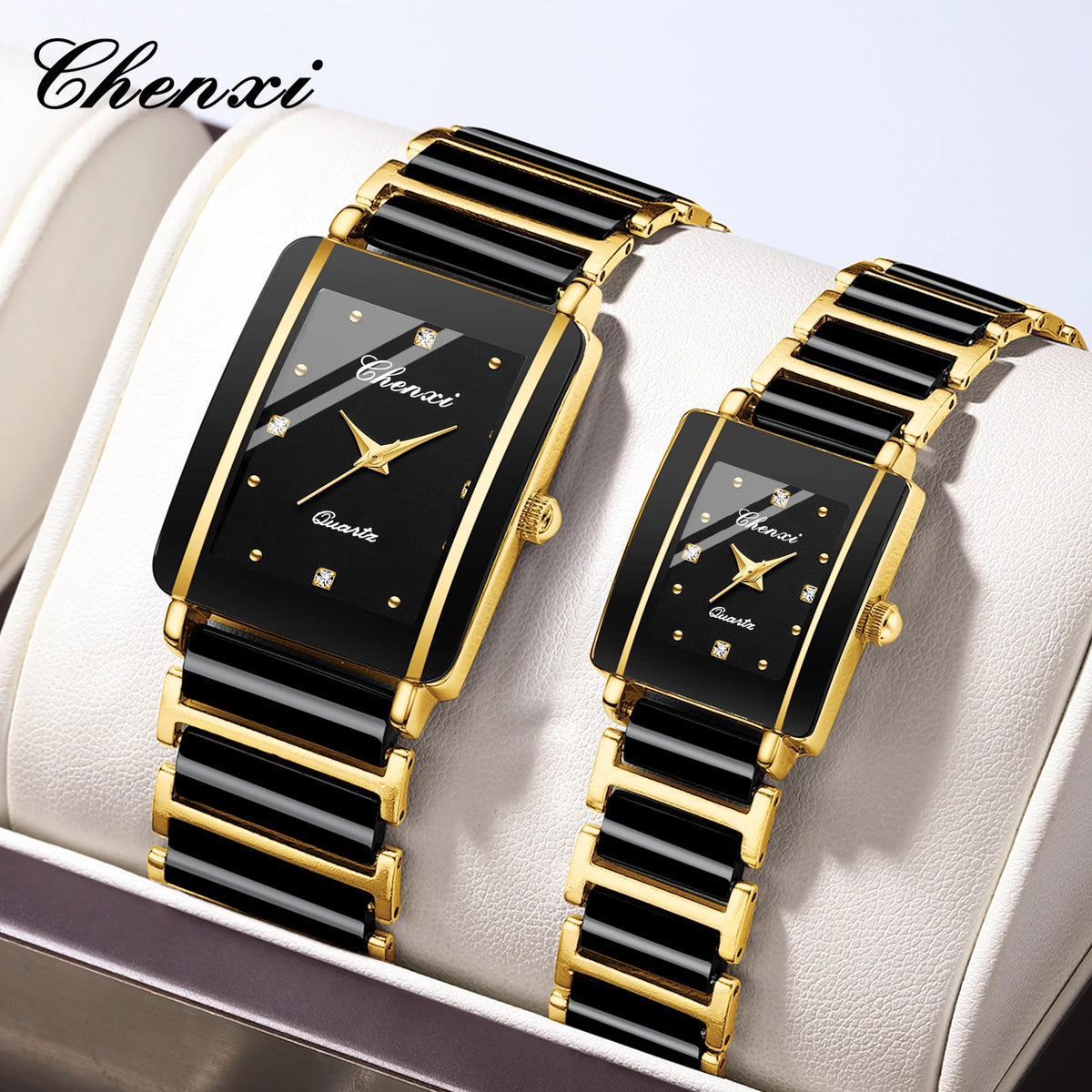 A pair of black and gold luxury quartz watches displayed on a white box.