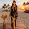 A plus size model wearing an orange and black African silk printed two-piece set standing on a wooden deck with a tropical su