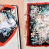 A floral print silk scarf featuring teal and pink botanicals on a black background.
