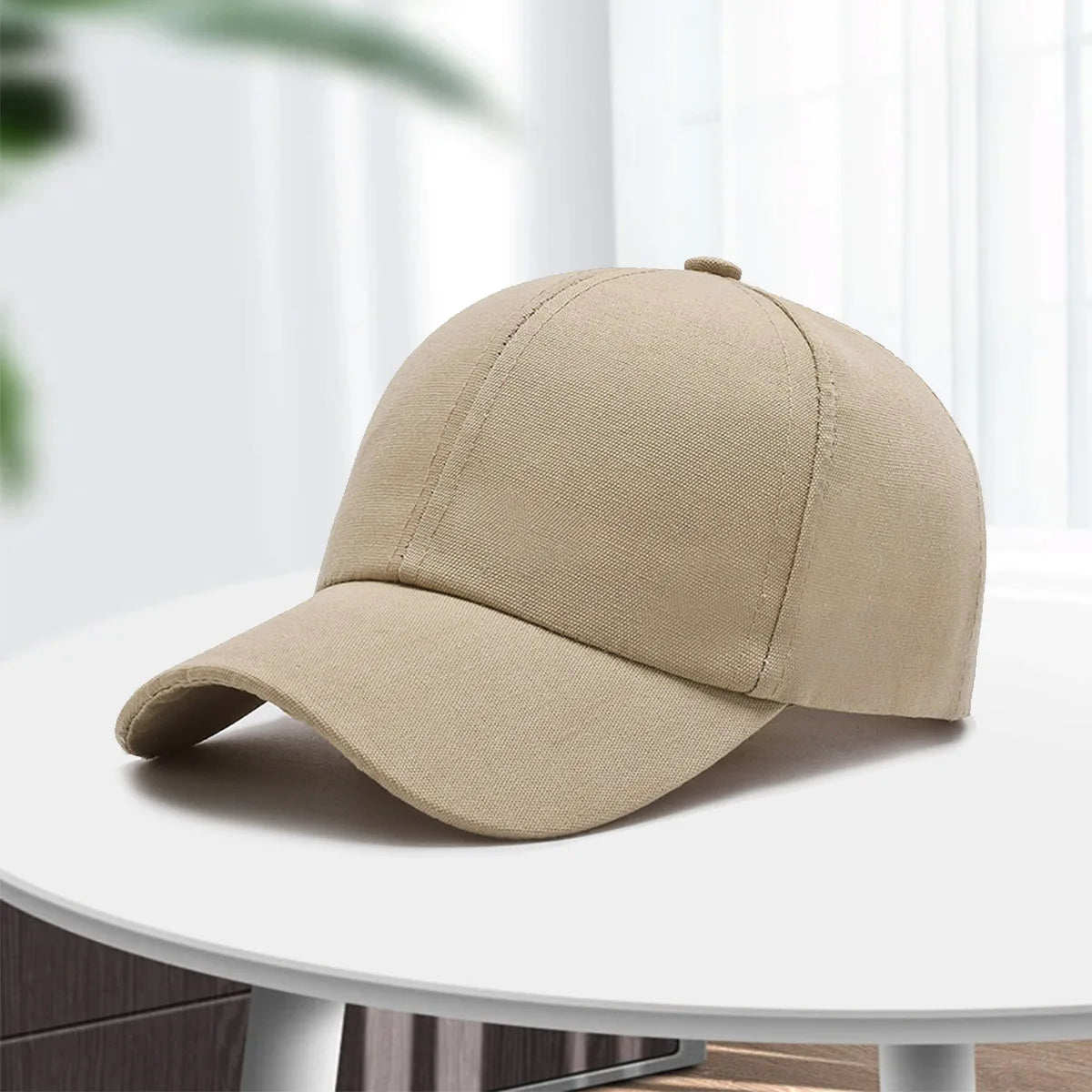 A beige cotton curved visor hat is displayed on a white table.