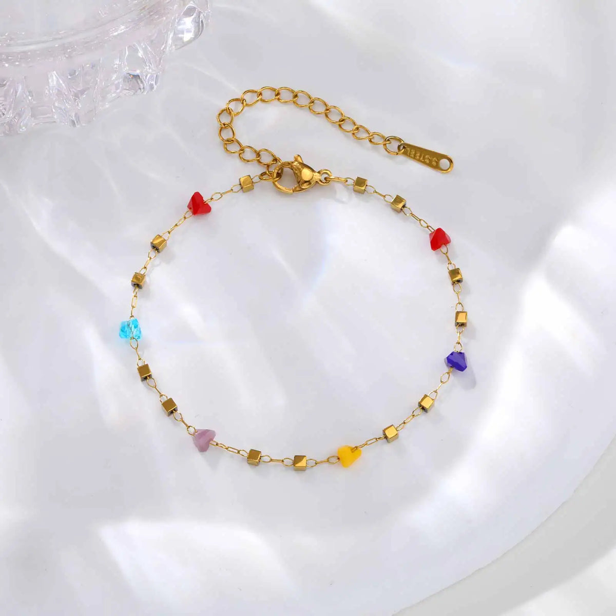 A gold chain choker necklace featuring various small, irregular colored stones like red, blue, and purple.