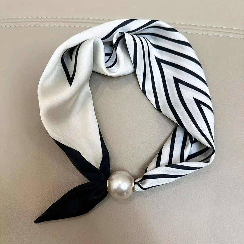 A white and black striped scarf tied in a knot with a pearl magnetic clasp
