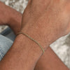 A close-up of a man's wrist wearing a gold-toned stainless steel Cuban link bracelet.