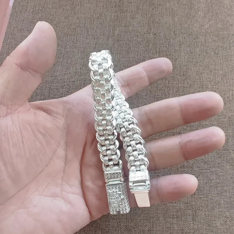 Eine Hand hält ein silbernes Totenhelm-Armband aus Vintage-Stil für Männer, das die detaillierte Kettendesign zeigt.