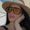 A woman wearing aviator style UV protection sunglasses with a straw hat and dark hair.