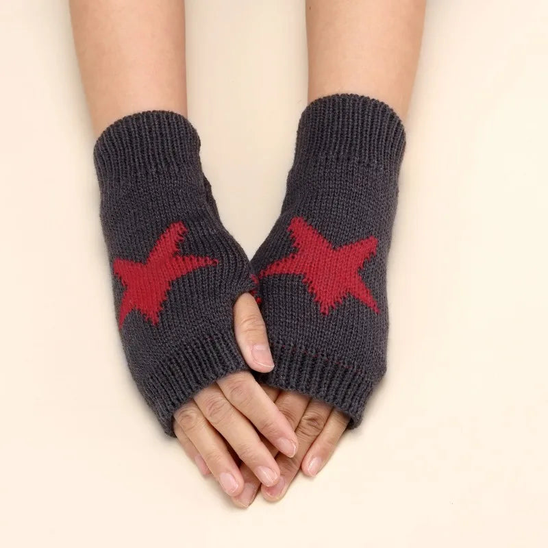 A pair of dark gray knitted half finger gloves featuring a red star pattern, shown on a person's hands.