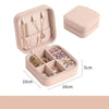A pink compact leather jewelry travel organizer with a lid and multiple compartments for storing accessories.
