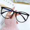 A hand holds a pair of black-framed spectacles with blue accents against a white background.