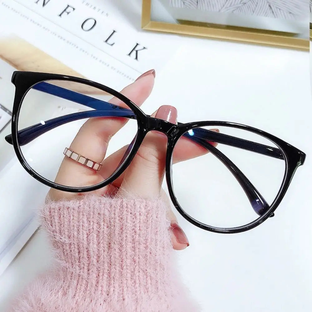 A hand holds a pair of black-framed spectacles with blue accents against a white background.