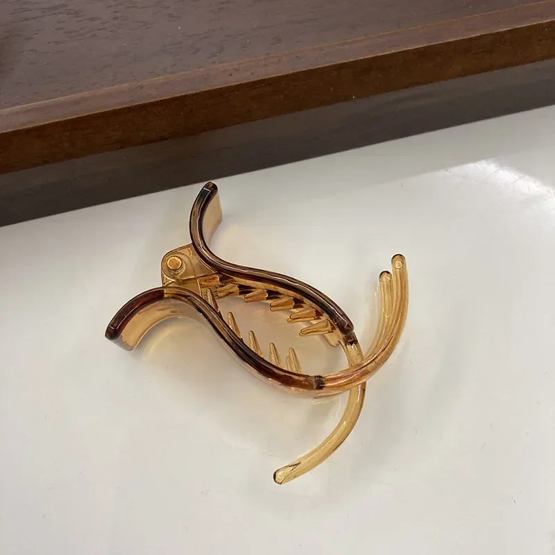 Transparent acrylic hair claw designed for ponytail styling, featuring a curved shape.