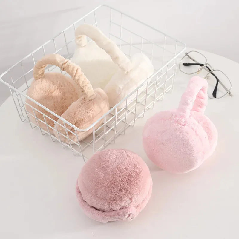A white wire basket filled with pink and cream plush fur ear warmers or earmuffs.