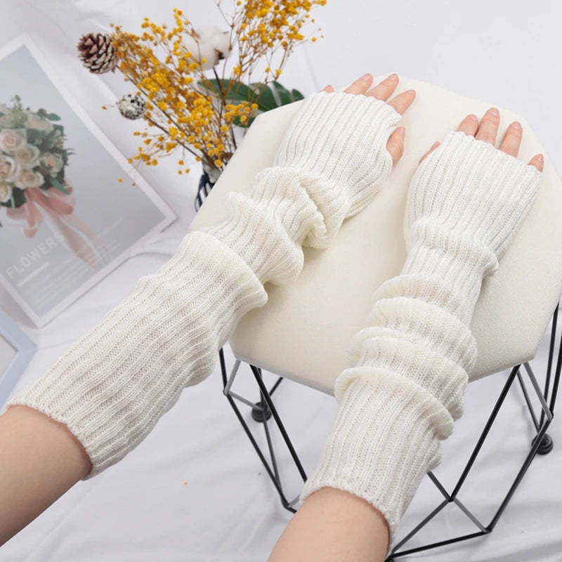 A pair of cream-colored knitted fingerless gloves displayed on a black wire stand.