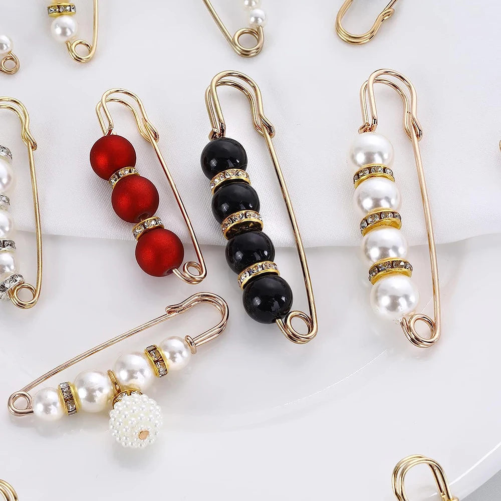 A collection of heavy duty pearl safety pins in gold-toned wire, featuring various colored and sized pearls.