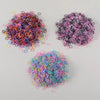A pile of colorful disposable rubber hair ties in various shades of pink, purple, and black.