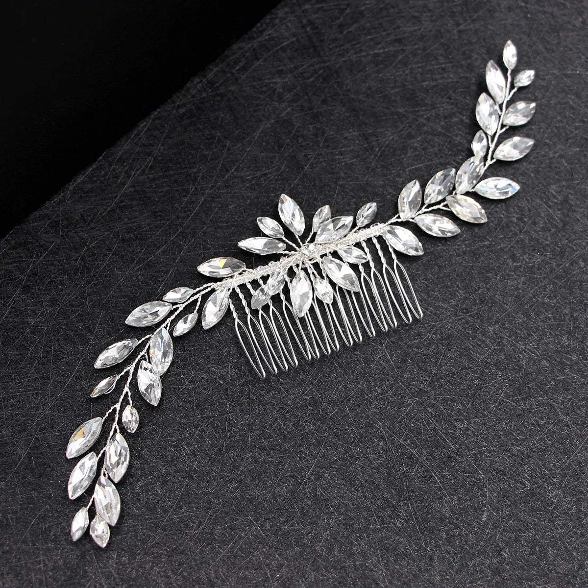 Une délicate peigne pour cheveux de mariée en cristal avec des feuilles scintillantes et des filaments fins.