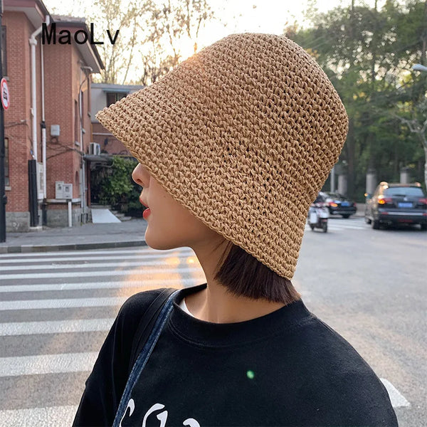 A woman wearing a beige hand-woven straw visor hat outdoors.