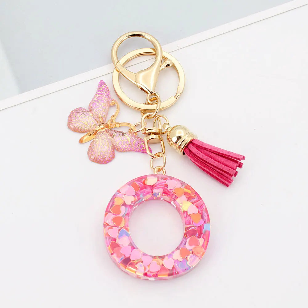 Gold acrylic keychain featuring a pink butterfly charm and a magenta tassel.