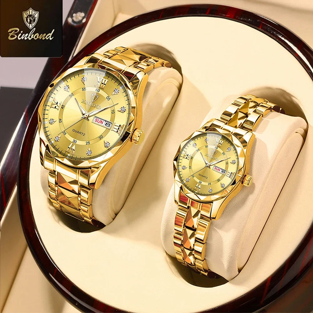 A pair of gold-toned stainless steel couple watches with sunburst dials displayed on a wooden stand.