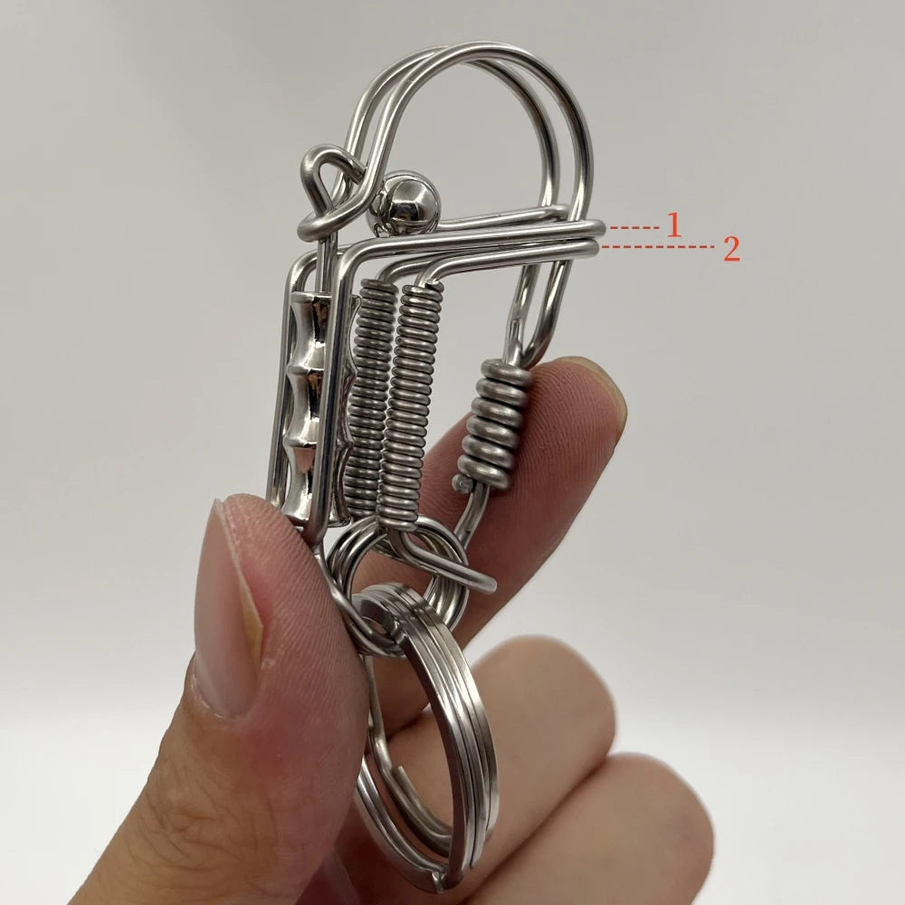 Une main tient un porte-clés mécanique en acier inoxydable avec un ressort et une boucle circulaire.