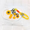 A collection of yellow and black fitness keychains and weightlifting accessories displayed on a white plate.