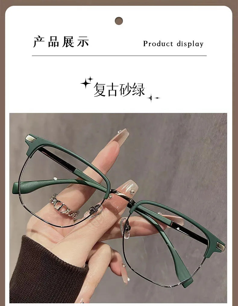 Eine Hand hält eine grüne Anti-Blaulicht-Lesebrille mit schwarzen Rahmen vor einem grauen Hintergrund.