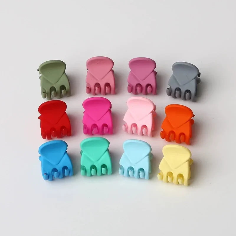 A set of eight adjustable hair claw clips in various pastel and muted colors, including green, pink, gray, orange, blue, and 