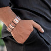 A man wearing a pure copper magnetic bracelet on his wrist, visible against a dark suit sleeve.