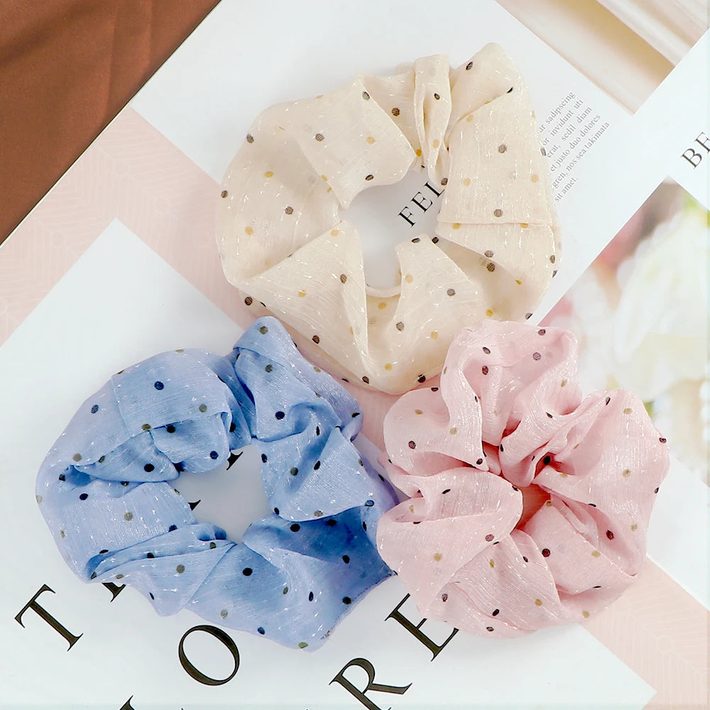 Three colorful knitted hair scrunchie headbands in light pink and blue polka dots displayed on a white surface.