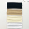 A set of four knitted hair bands in black, tan, cream, and white arranged horizontally on a white surface.