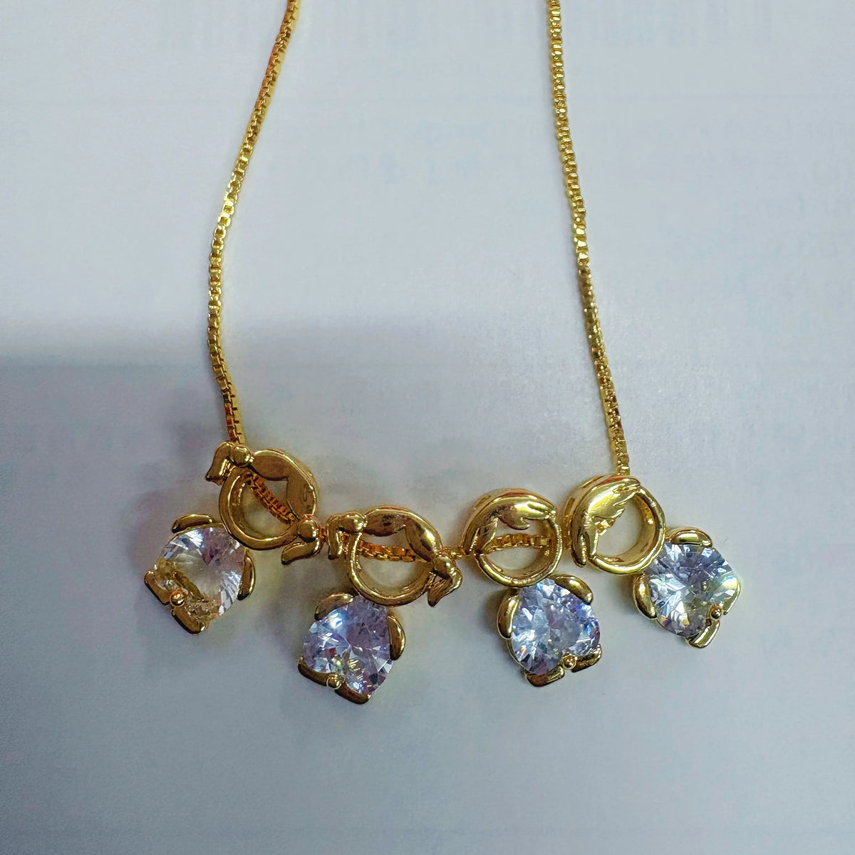 Goldenes Herz-Anhänger-Halskette mit kleinen klaren und violetten Edelsteinen auf einer zarten Kette.