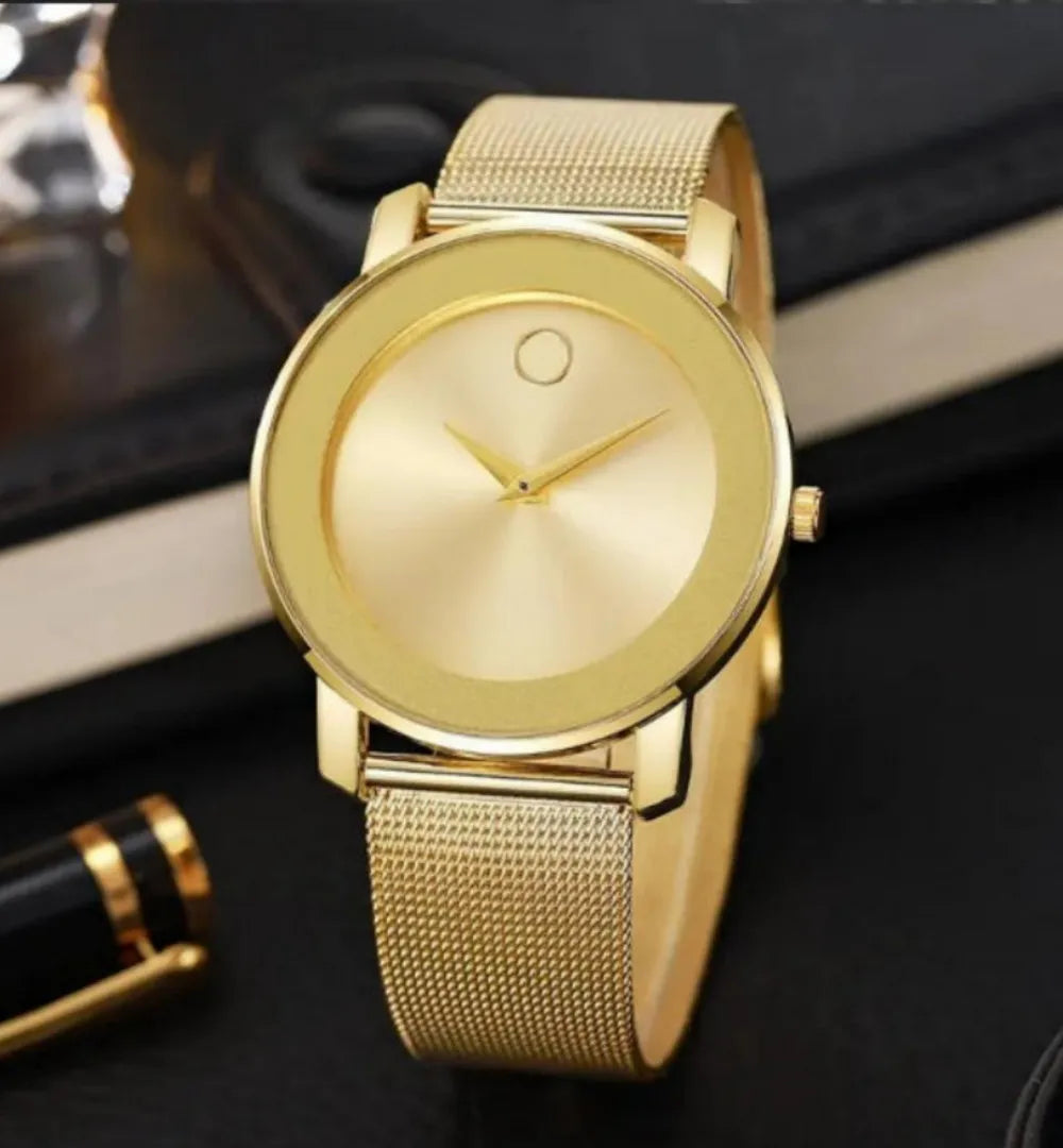 A gold-toned men's quartz wristwatch with a round face and slim mesh strap resting on a dark surface.