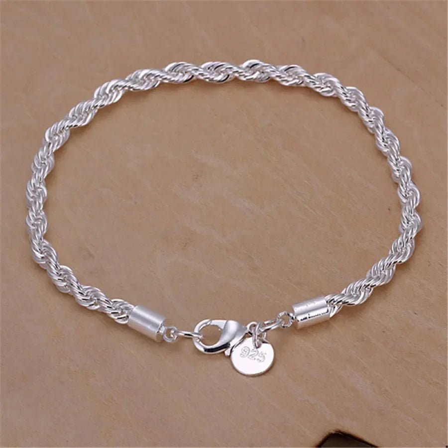 A silver twisted rope necklace and bracelet set made of 925 sterling silver resting on a brown surface.
