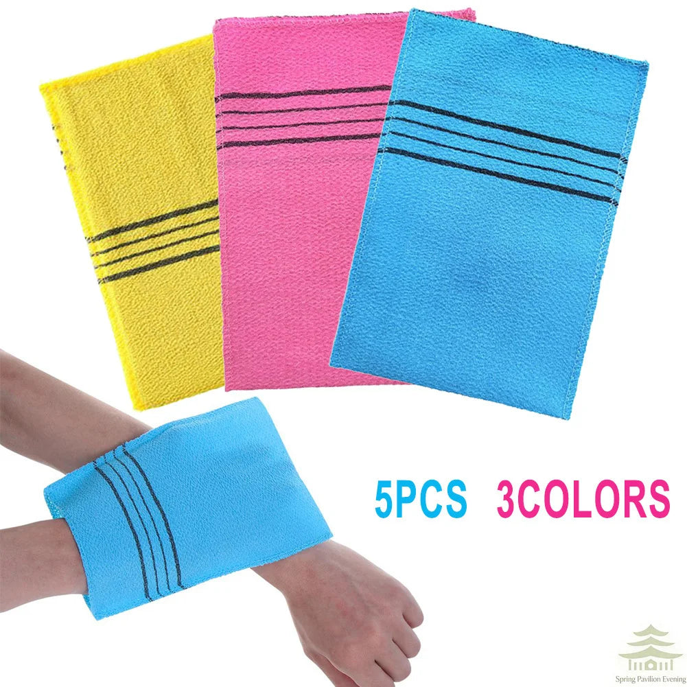 A set of five exfoliating bath washcloths in yellow, pink, and blue with black stripes shown next to a hand.