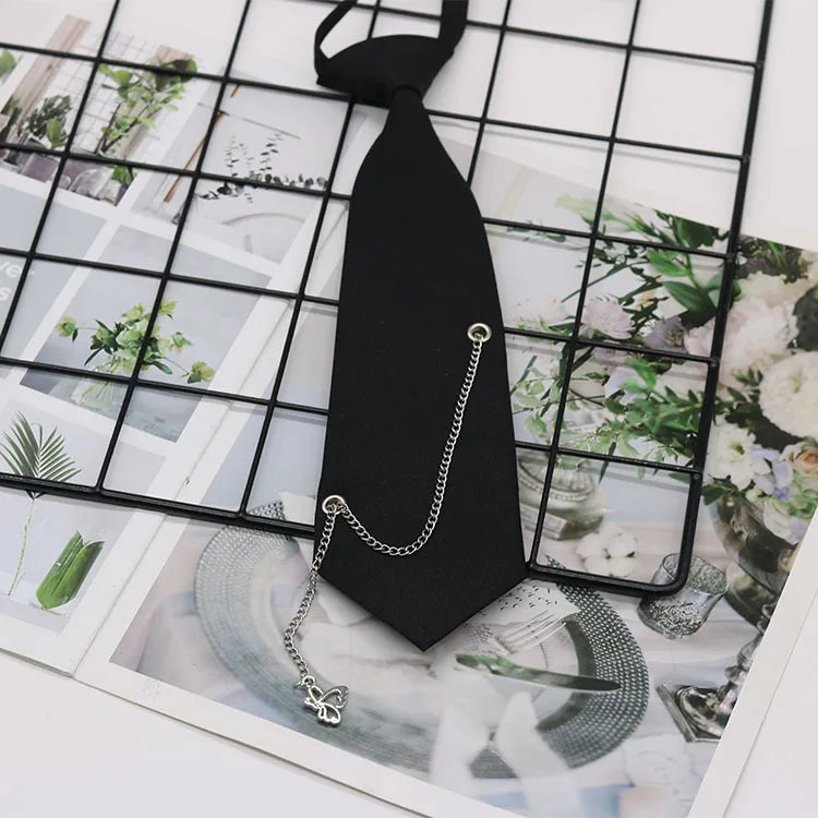 A black classic chain necktie is displayed against a grid background featuring floral and natural elements.