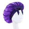 Purple satin wide-brimmed hair wrap headscarf tied in a bow displayed on a white mannequin.