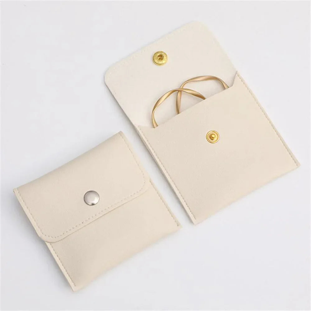 A light beige PU leather jewelry pouch with a snap button closure shown in an open, angled view.