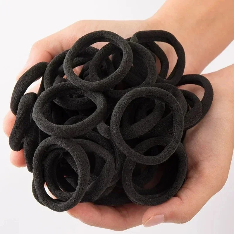 Eine Hand hält ein Bündel schwarzer, strapazierfähiger elastischer Haarbänder für Pferdeschwänze.
