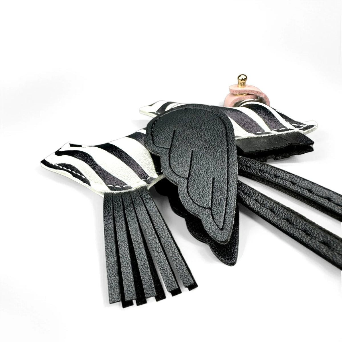 A black leather winged pony keychain with white stripes and a pink metal clasp.