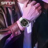 Nahaufnahme eines Mannes mit einer silbernen Chronographenarmbanduhr, einem dunklen Lederjacken und einem weißen Hemd.