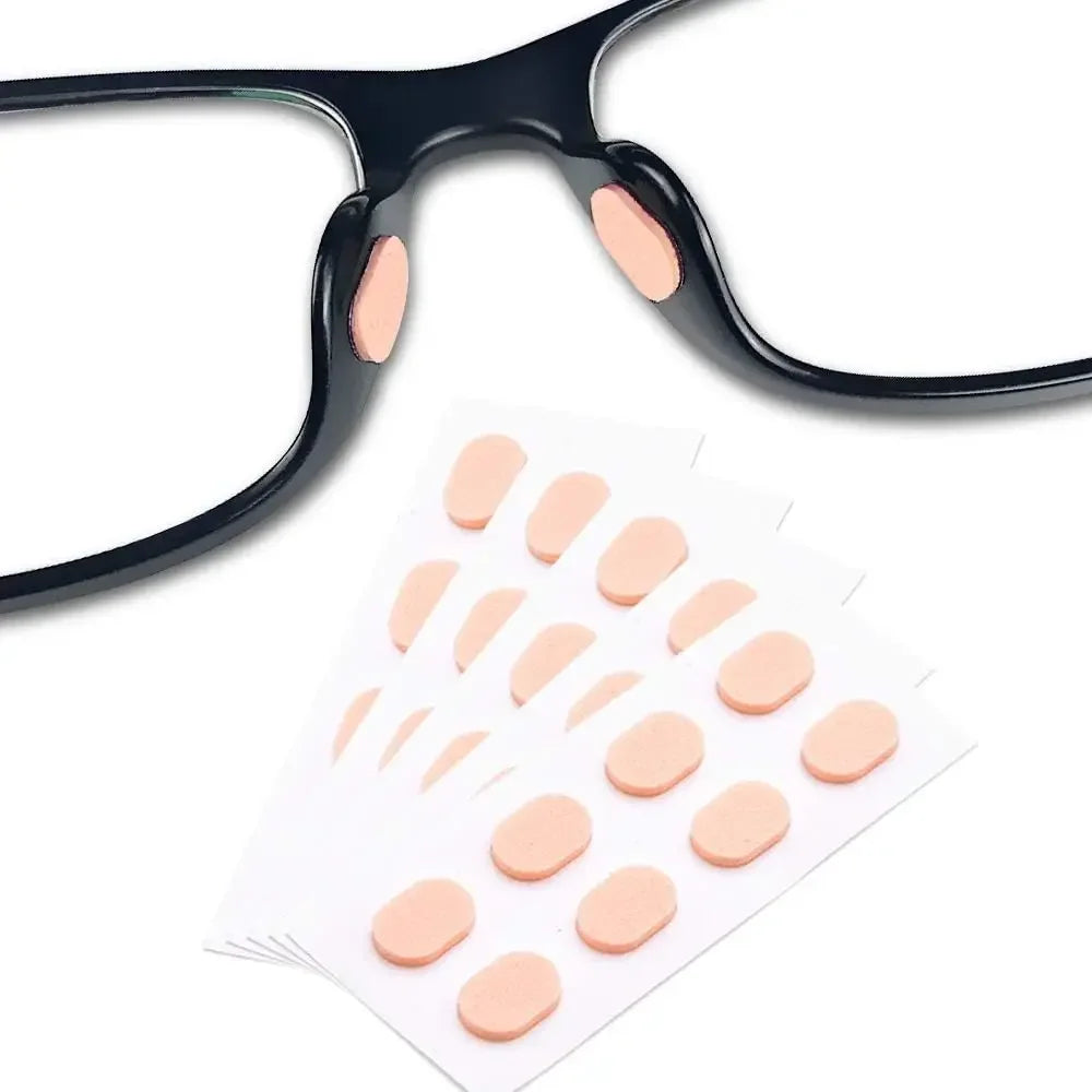 Un par de gafas negras con almohadillas anti-resbalar rosas reutilizables junto a un blíster de las mismas almohadillas.