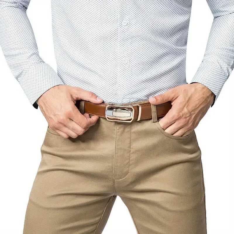A man wearing a light blue collared shirt and tan trousers is adjusting a brown leather ratchet belt.