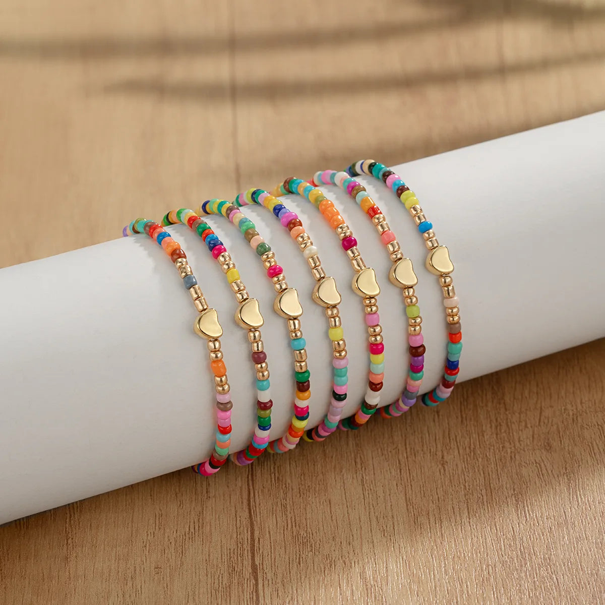 A collection of colorful resin beaded bracelets stacked on a white wrist.