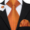 A close-up of a men's silk jacquard tie in orange and gold tones worn with a black suit jacket.